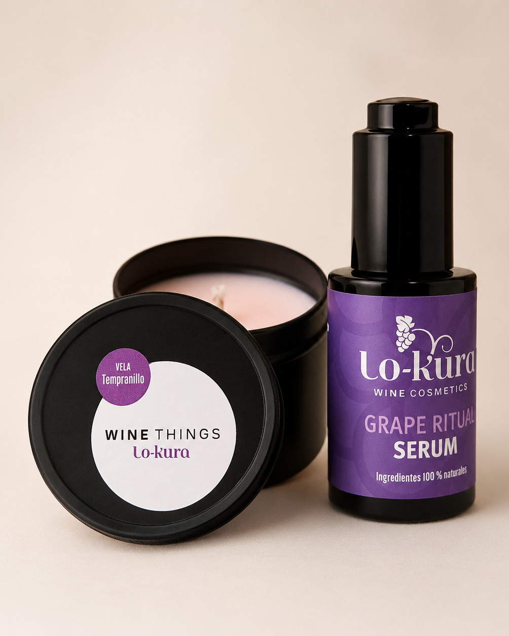 Vela en lata negra con tapa apoyada sobre ella con pegatina y bote de grape ritual serum a su lado. el bote del serum es de cristal con tapa alta con botón de aplicación y etiqueta morada.