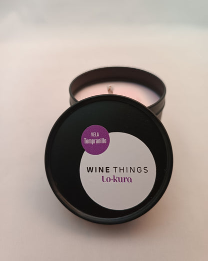 Vela con ligero color rosaceo en lata cilíndrica negra con tapa con etiqueta winethings lo-kura vela tempranillo