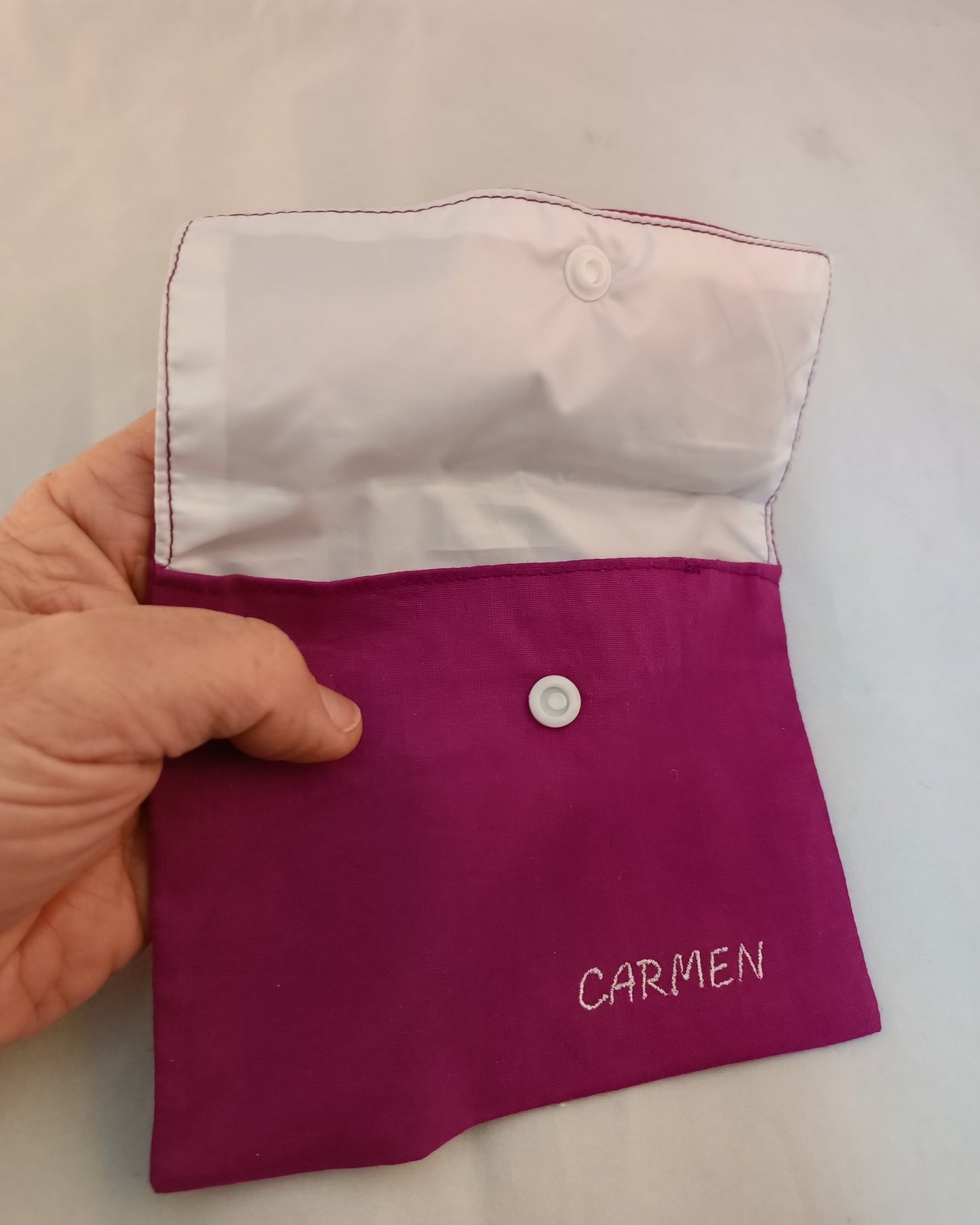 neceser de viaje de color morado con solapa abierta y nombre bordado
