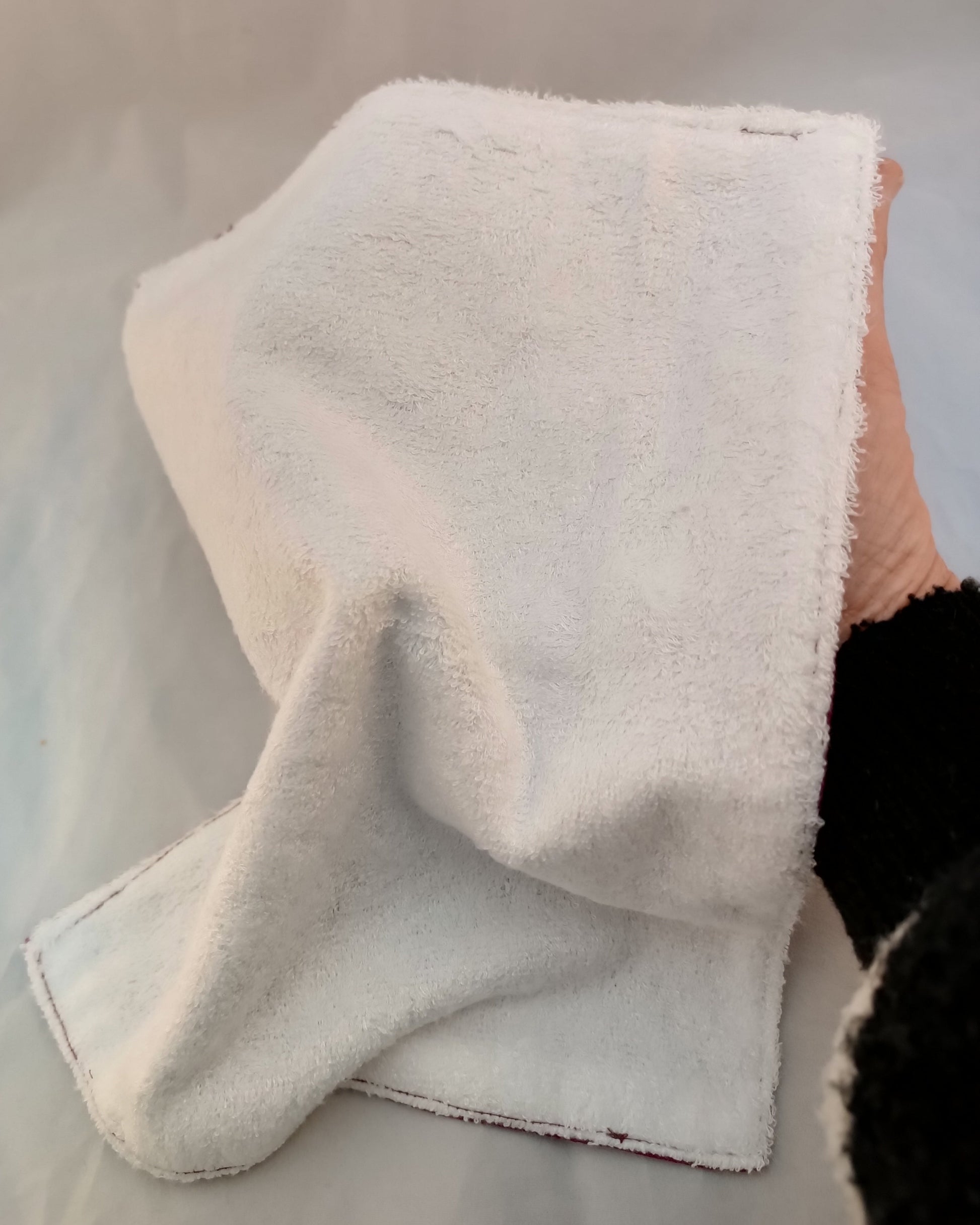 mano sujetando toalla facial por la parte de la fibra de bambú